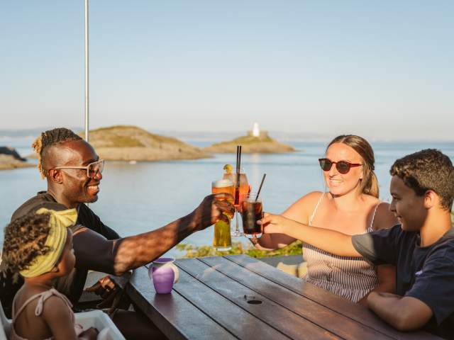 Family toasting their glasses with coast in the background