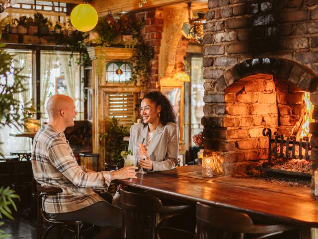 Young couple enjoying a drink by the fire at Gin and Juice