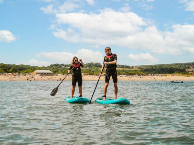 young couple stand up paddle boarding on oxwich bay