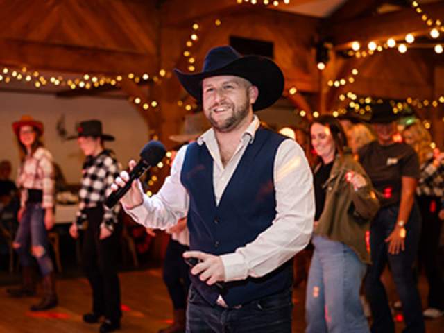 A man in a cowboy hat singing into a microphne