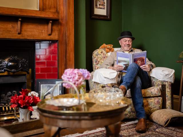A man sitting in a chair reading at the Dylan Thomas Birthplace