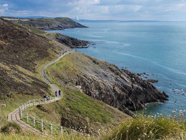 two walkers making their way along a coastal path on the gower