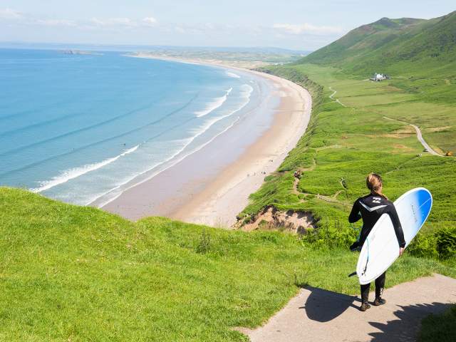 Surfer walking down to Rhossili Bay Beach