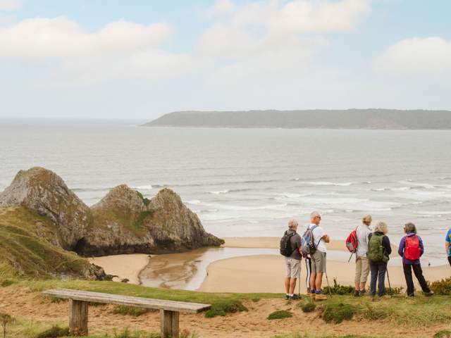 A group of walkers looking out at Three Cliffs Bay.