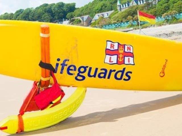 RNLI lifeguards surfboard and live preservers on the beach
