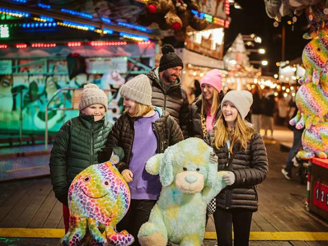 A family at the winter funfair with stuffed toys