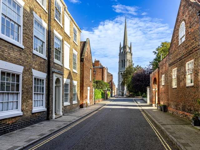 an empty street with a church in the background under blue skies