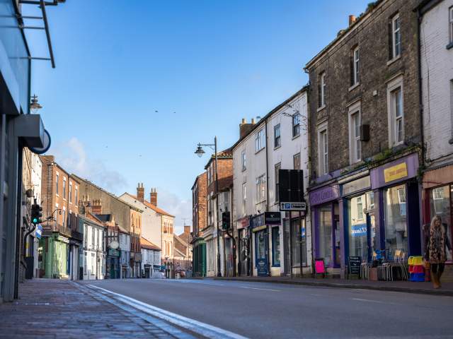 A high street lined with shops in early morning light