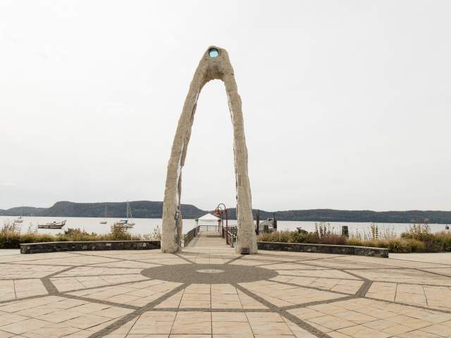A piece of artwork in the shape of an arch sits beside the Hudson River at Henry Gourdine Park.