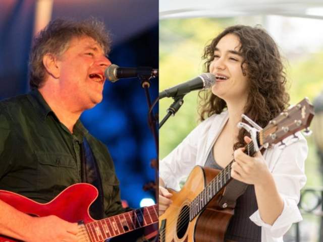 Two performers hold guitars and sing into microphones.