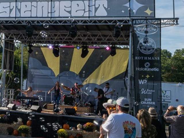 The Steinyfest stage during the day with a band performing and bubbles in the background.