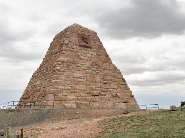 A stone pyramid stands on a mound in grassy plains, a weird and unique place to visit in Wyoming.