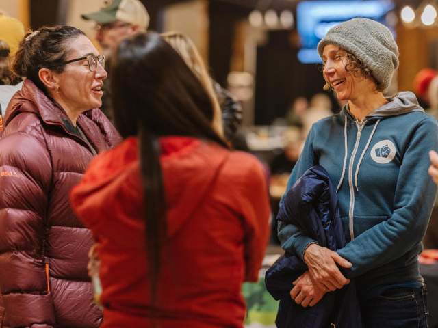 Three ladies  talking wearing multiple layers of clothes.