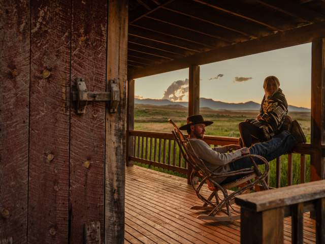 Couple sitting on the porch of a cabin.