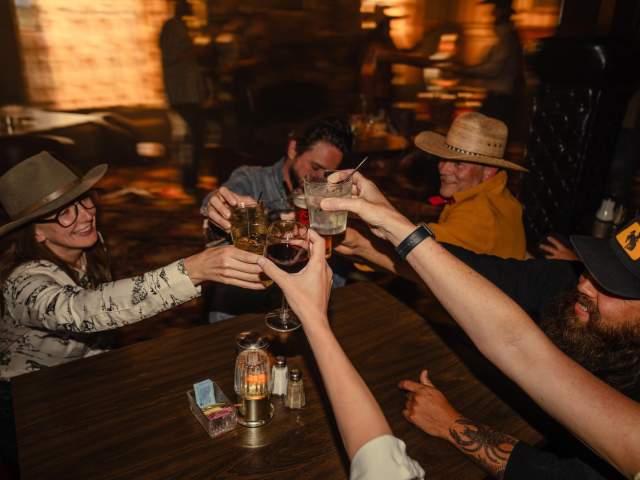 Group of people cheersing drinks around a table.
