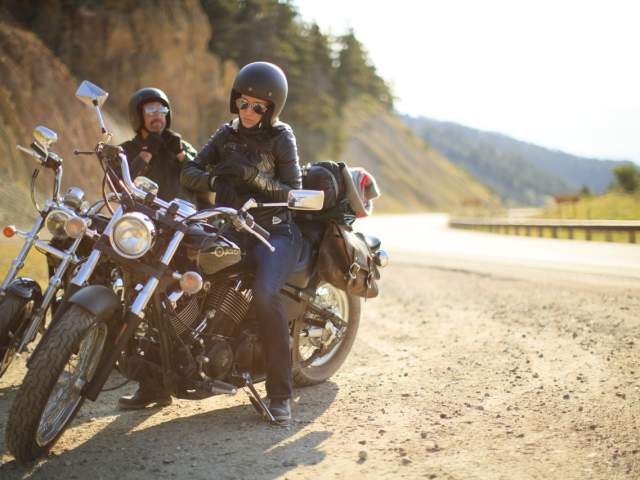 Couple on side of a scenic byway on motorcycles, enjoying the views near Buffalo, Wyoming.