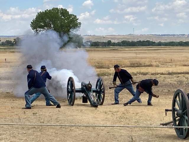 A cannon blows off smoke across the field as officials dressed in military outfits participate in a demonstration at the Fort Laramie Historical Site in Fort Laramie, Wyoming.