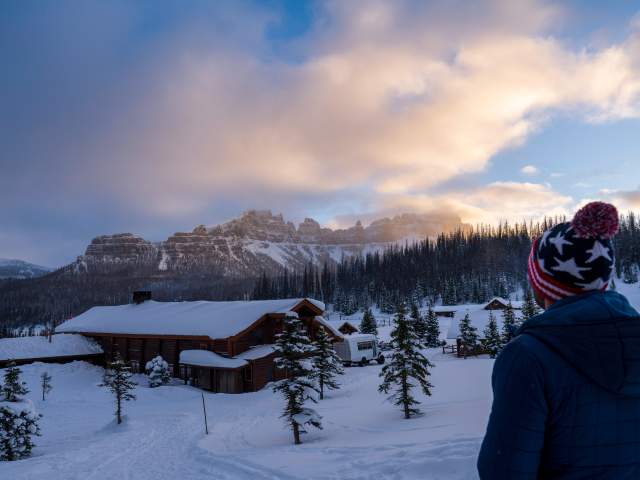 Man overlooking Brooks Lake Lodge in winter with mountain range in the background