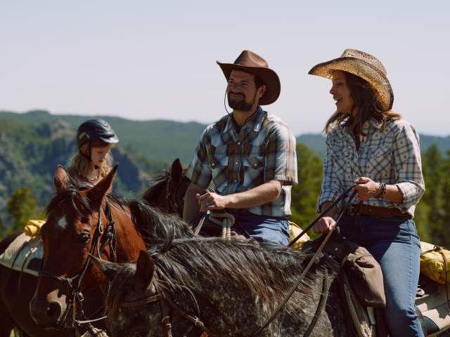 Family riding horses at a dude ranch.