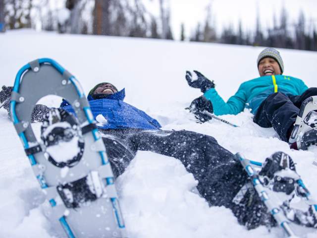 Dad and son snowshoeing in the woods.