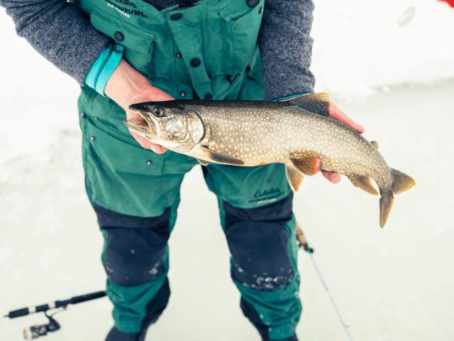 Angler ice fishing on a frozen lake with fish in hands in Wyoming.