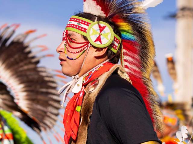 A close-up of a man wearing a headdress and traditional clothing at the Annual Eastern Shoshone Indian Days Powwow.
