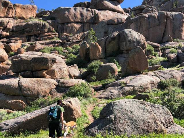 A man and his dog walking through the rock formations of Vedauwoo, a unique place to visit in Wyoming