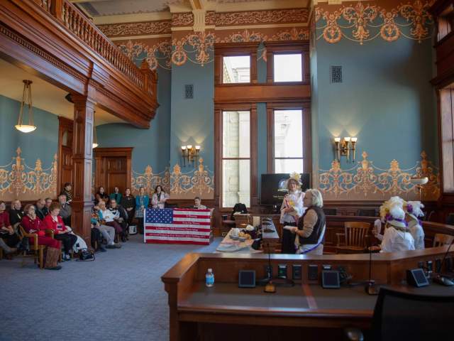 Women gathering in historic courtroom setting.