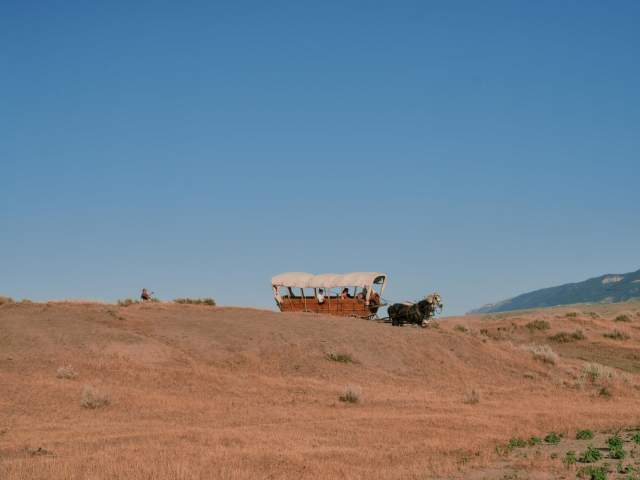 Covered wagon on a dry landscape, filled with hidden histories in Wyoming.