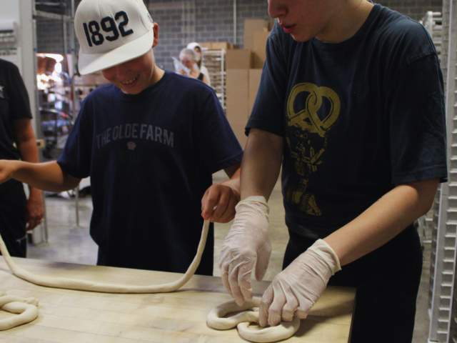 a boy enjoying hand-twisting a pretzel during the Makers Spirit Event