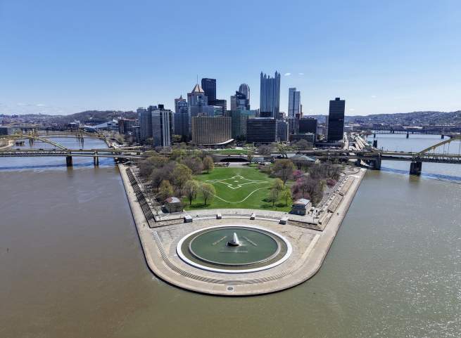 Aerial view two rivers running parallel to a fountain in a park with the city skyline of Pittsburgh