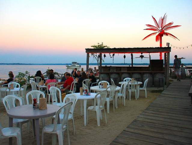 tables and chairs on a beach at sunset