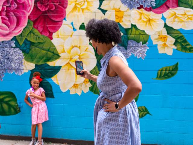 Mom taking photo of daughter in front of the Walt Whitman mural in Fort Wayne, Indiana