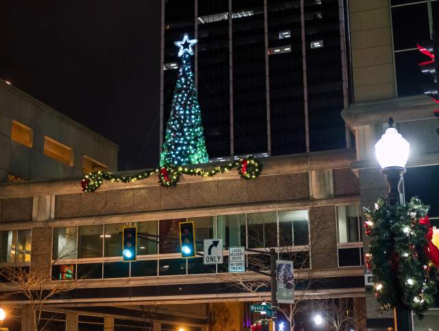 christmas tree on top of an enclosed skywalk at night in downtown fort wayne