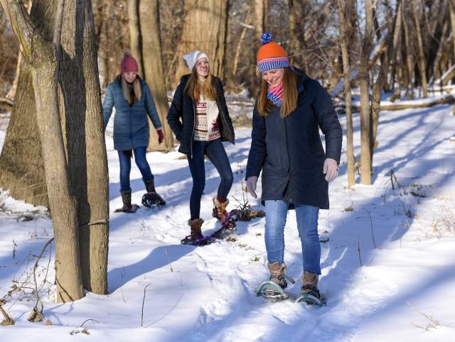 girls wearing snowshoes walking through the snow