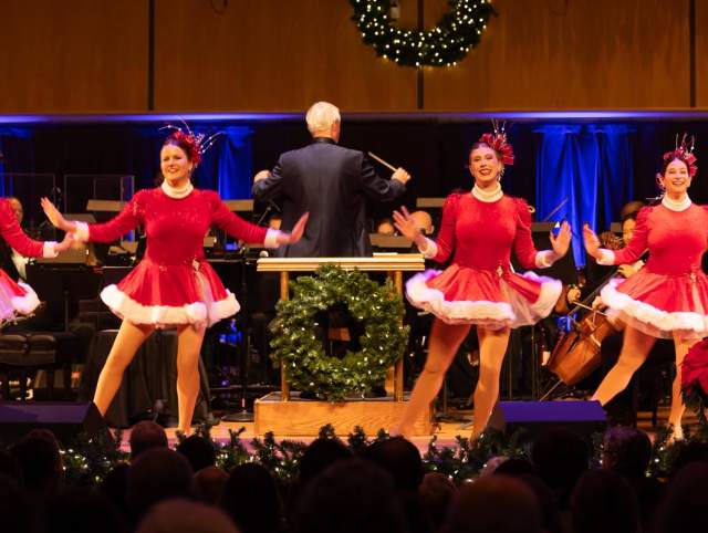 Woman dancing on stage with the Fort Wayne Philharmonic during a Holiday Pops performance.