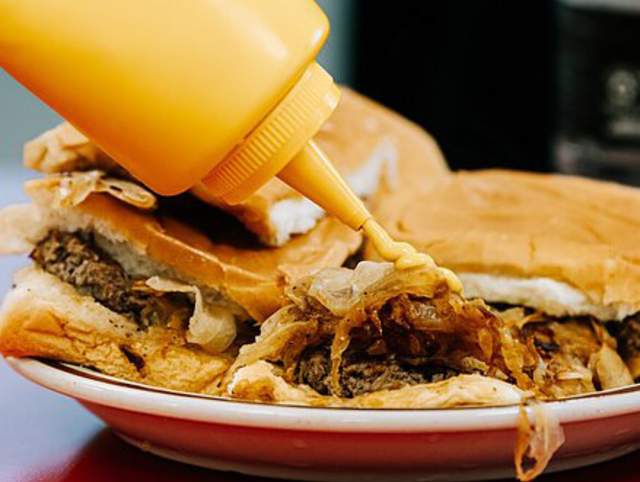 Pouring mustard on a Powers Burger in downtown Fort Wayne