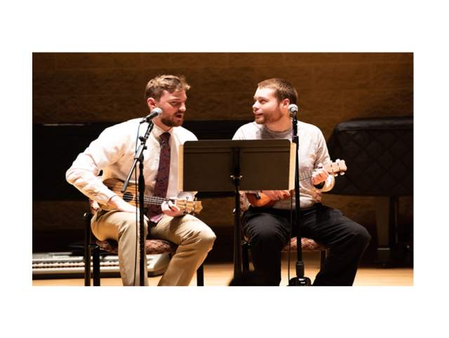 Two men playing ukulele together
