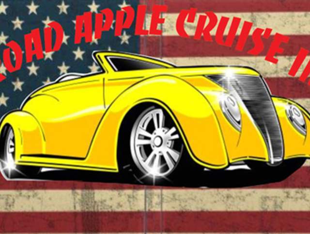 Image of yellow classic car sitting in front of US flag