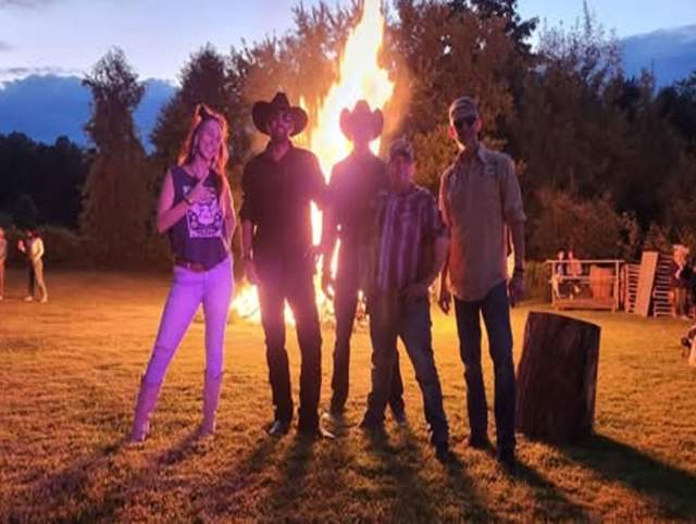 Promotion image of Whiskey Bound Band members posing before a bonfire