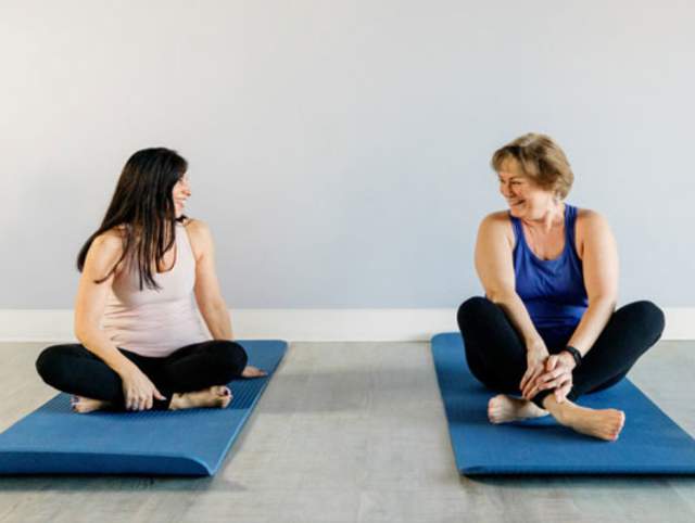 Two women on mats in a pilates studio
