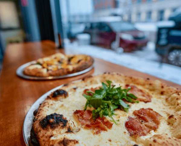 Two pizzas on a table by the window