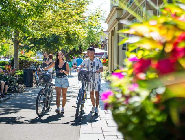 Two cyclists walking their bikes down the main street