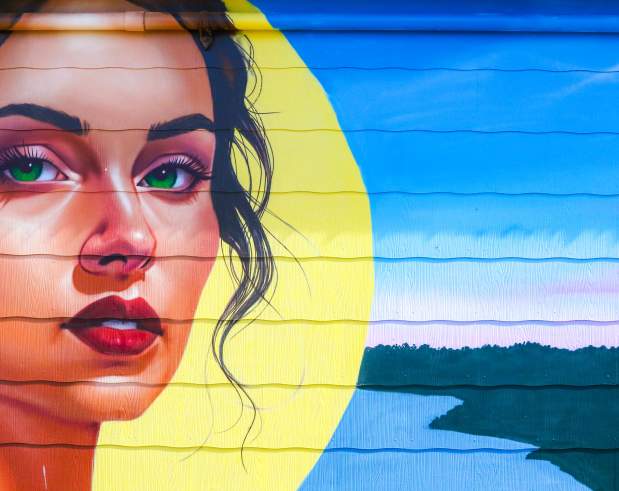 a mural depicting a girl on the Neches River in front of a sun