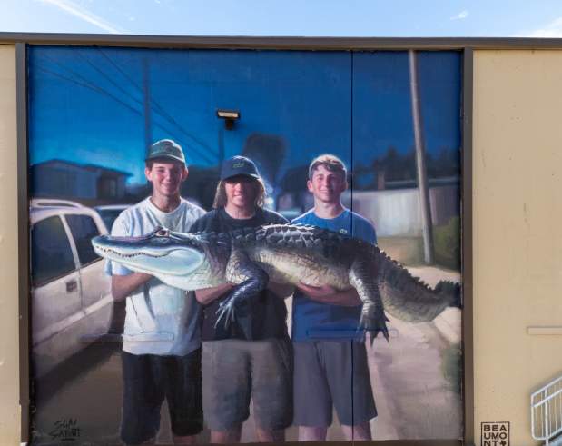 a mural showing three teenage boys holding an alligator and smiling