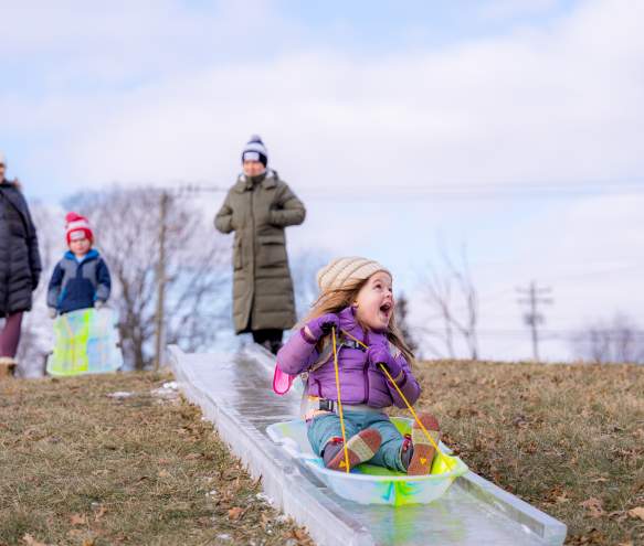 A little girl sledding down the ice luge at Freezefest