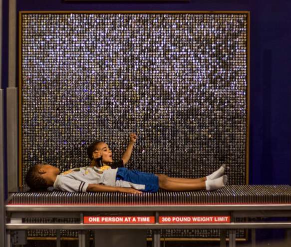 Two little boys exploring a bed of nails exhibit at WonderLab Museum