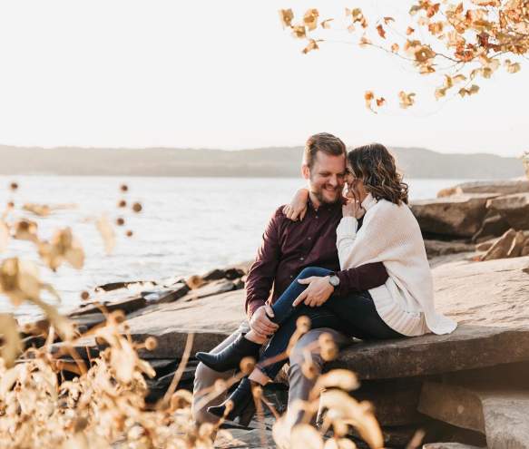 A couple sitting on the rocky shore of Monroe Lake during fall