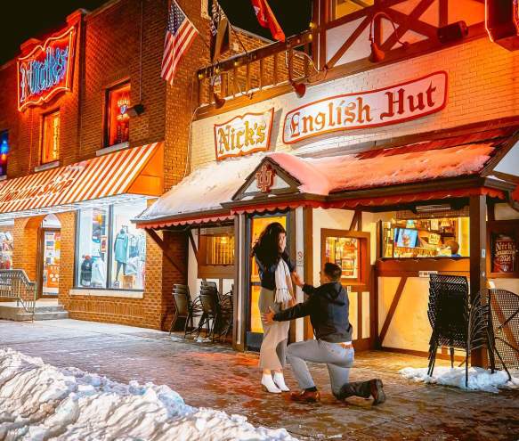 A man proposing to a woman in front of Nick's English Hut