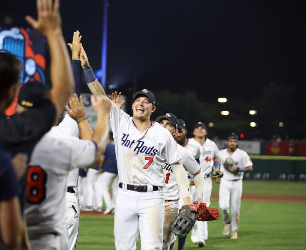 A baseball player going in for a high five with fans